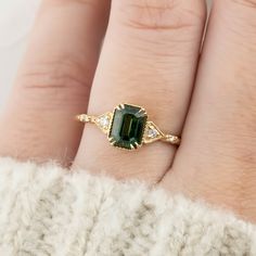 a woman's hand with a gold ring and green tourmaline stone on it