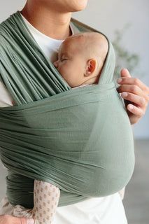 a woman holding a baby in a green wrap