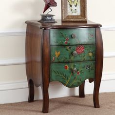 a green painted chest with flowers and butterflies on it, next to a framed painting