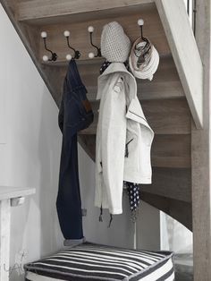 a coat rack with hats and scarves hanging from it's hooks under a stair case