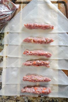 five raw meat patties are lined up on parchment paper and ready to go into the oven