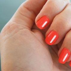 a woman's hand with bright orange nail polish