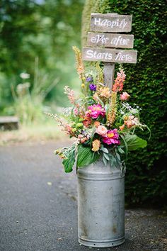 a bucket with flowers in it and a sign that says happy birthday on the side