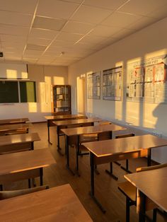 an empty classroom with wooden desks and bookshelves