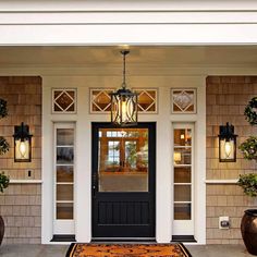 the front door is decorated with potted plants and hanging lantern lights on either side