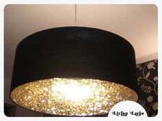 a black lamp shade with gold flecks hanging from it's ceiling in a living room