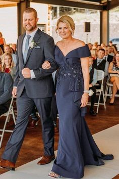 a man and woman in formal wear walking down the aisle at an event with people watching