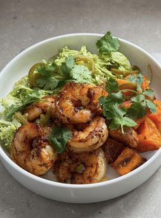 a white bowl filled with shrimp, carrots and guacamole garnished with cilantro