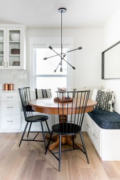 a dining room table with four chairs and a bench in front of the window,