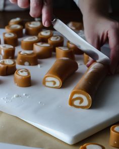 a person is cutting up some food on a white board with orange and white icing