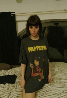 a woman standing on top of a bed wearing a shirt with the words pulp fiction printed on it