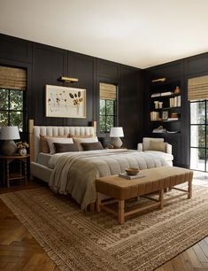 a large bedroom with black walls and wooden flooring is furnished with an ottoman bed