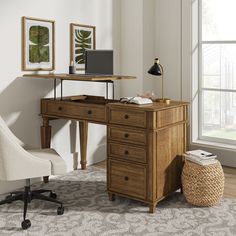 a desk with a chair and computer on top of it in front of a window