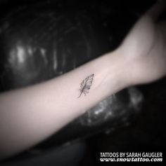 a small feather tattoo on the arm