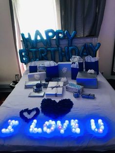 a birthday party with blue and white lights on the bed in front of a happy birthday sign