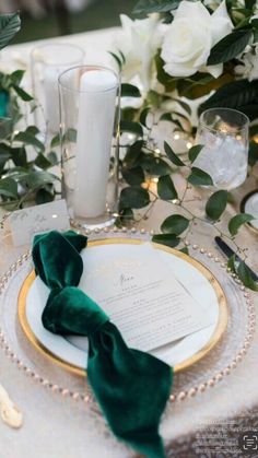 the table is set with white flowers and green napkins