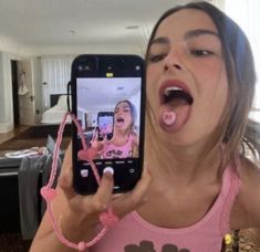 a woman taking a selfie with her cell phone in front of her mouth and tongue hanging out