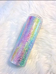 thermos cup is sitting on top of a white fur covered surface with colorful glitter