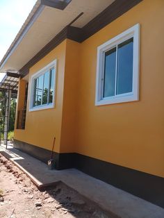 a yellow house with white windows and black trim on the side of it, under construction