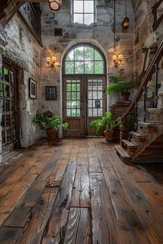 an old stone building with wooden floors and windows in the center is filled with potted plants