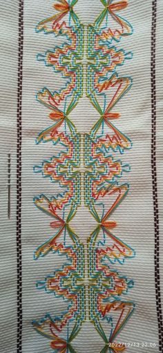 a close up of a piece of cloth with different colored designs on it and lines in the background