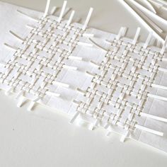 several pieces of white paper are arranged on a table with sticks sticking out of them