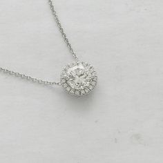 "Simple and elegant pendant made of 14K white gold. Features a 7mm, round Forever One Moissanite (1.20ct) surrounded by a halo of 20 diamonds,(0.15ct, G-VS quality) set in cut down micro pave style around the center stone. Measurements: 10mm. Price includes a 14K gold chain, 16 or 18\" long. Certificate of authenticity of moissanite is included with the ring. PROUDLY MADE FROM SCRATCH IN NEW YORK CITY. Please allow 2 weeks to complete this order. Document of authenticity of moissanite is include Diamond White Necklace With Halo Setting And Round Stone, White Diamond Necklace With Round Cut Halo Design, White Diamond Necklace With Halo Design, White Gold Diamond Solitaire Necklace With Halo Design, White Diamond Halo Necklace In Sterling Silver, White Solitaire Necklace With Halo Design, Formal Solitaire Necklace With Halo Round Cut, White Round Halo Diamond Necklace, White Diamond Halo Necklace In Fine Jewelry Style