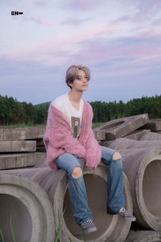 a young man sitting on top of cement pipes