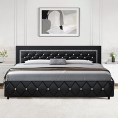 a large bed with black leather headboard and foot board in a white walled room