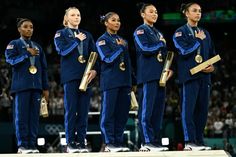 women's gymnastics team standing on the podium with their medals in front of an audience