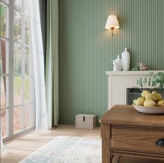 a bowl of lemons sits on a table in front of a window with green wallpaper