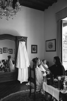 a bride getting ready for her wedding in the bridal gown hanging on the wall