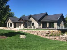 a large house sitting on top of a lush green field next to a stone wall