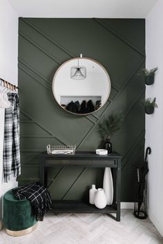 a black and white entryway with green accent wallpaper, an oval mirror above a console table