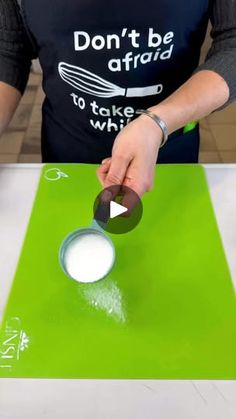 a woman is using a spoon to stir something in a bowl on top of a green cutting board