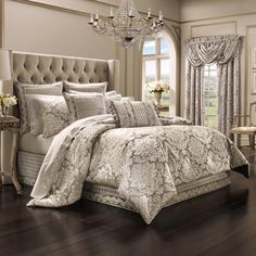 a bedroom with a bed, chandelier and window in the background on a hard wood floor