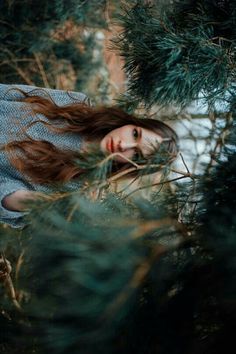 a woman with long hair standing in the woods