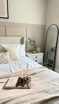 a bedroom with a bed, mirror and candles on the side table in front of it