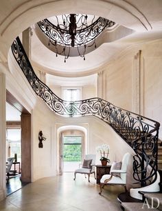 an elegant staircase with wrought iron railing and chandelier