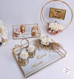 a table topped with gold and white flowers on top of a mirrored tray next to a mirror