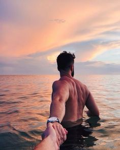 a man holding the hand of another person on top of a boat in the ocean