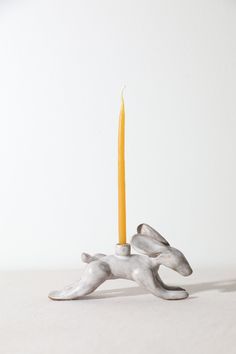 a candle that is sitting in the middle of a small animal figurine on a table