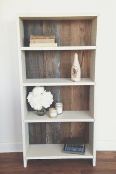 a white book shelf with flowers and books on it