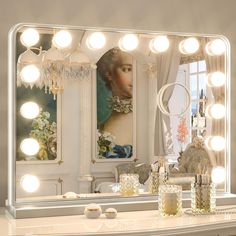 a vanity mirror with lights on top of it next to a table and vases