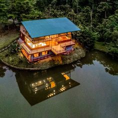 a house on an island in the middle of a lake with trees around it at night