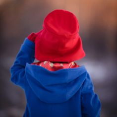 Paddington's favorite accessory is now your favorite accessory too! This classic bucket hat has a wide brim to keep the wind or sun off and a deep crown just like Paddington's (although we don't recommend it for marmalade sandwich storage). Hand crafted from the cheeriest red wool and lined in our signature Paddington satin print, it is made to last for generations. Packs flat for travel or tucking into the pocket of your Paddington Duffle Coat. **Size Note: If you are purchasing for a 4 year ol Marmalade Sandwich, Duffle Coat, Heads Up, Red Wool, Marmalade, Wide Brimmed, The Wind, Bucket Hat, Hand Crafted