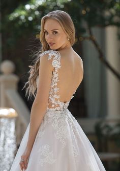 a woman in a wedding dress looking back at the camera with her hand on her hip