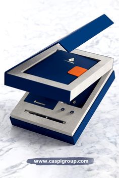 a blue and silver electronic device sitting on top of a marble countertop with an orange square in the middle