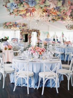 the tables are set with white chairs and blue tablecloths, which have flowers on them