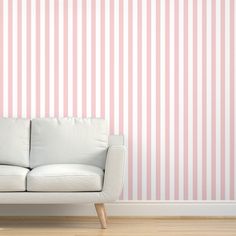 a white couch sitting in front of a pink striped wall